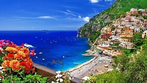 A coastal village with colorful buildings, a beach, and boats on the water. - Room to dream (San Valentino Torio)