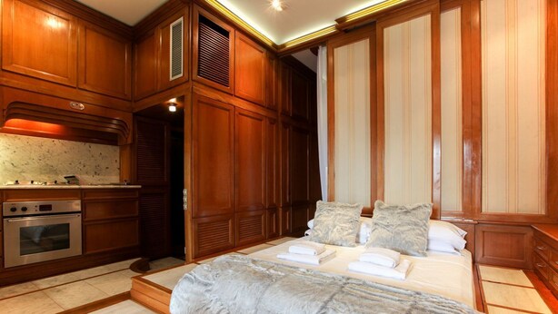 Une chambre avec un grand lit, des armoires en bois, un four encastré et un placard à portes coulissantes.