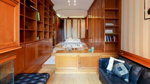 Une bibliothèque avec des étagères en bois, un bureau central et un canapé en cuir.