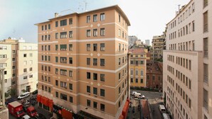 Un immeuble à plusieurs étages, doté d’une façade beige et de cadres de fenêtres blancs, entouré d’autres bâtiments.