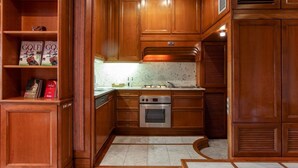 Une cuisine avec des meubles de rangement en bois, un four encastré et un plan de travail équipé d’une hotte aspirante.
