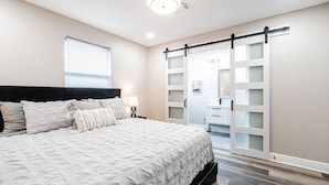 A bedroom with a large bed, a nightstand, a dresser, and a sliding closet door. - Charming 3-bedroom house with AC and WiFi in awesome Kenner (Kenner)