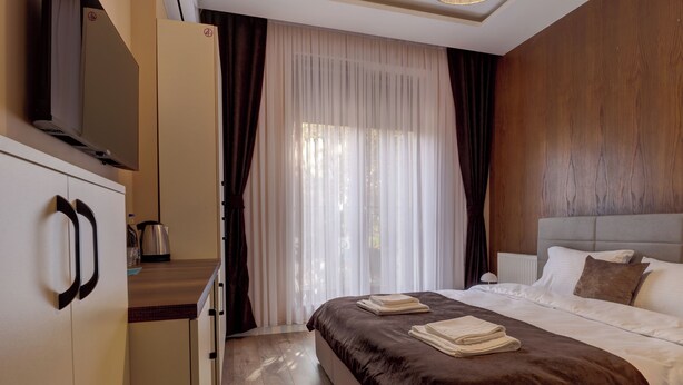 Een hotelkamer met een bed, een kledingkast, een televisie en een raam met gordijnen.