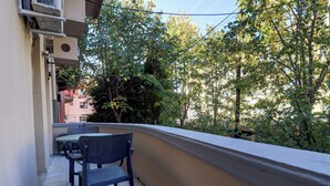 Een balkon met een tafel en stoelen, omringd door bomen en gebouwen.