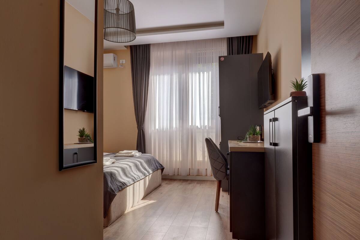 Een moderne hotelkamer met een bed, een bureau, een stoel, een televisie en een kledingkast.