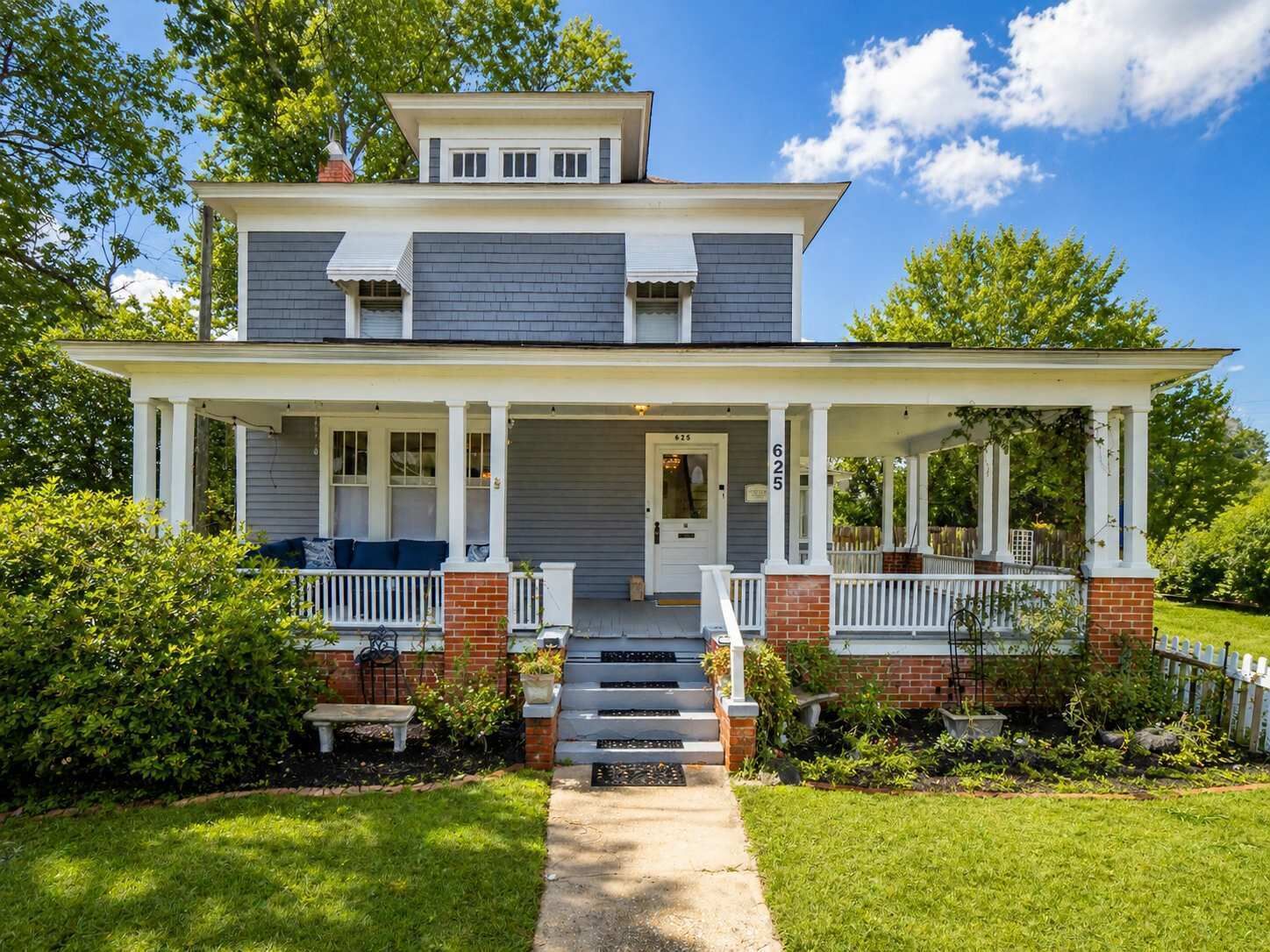 A two-story house with a front porch, a door, and a number '625' on the wall.
