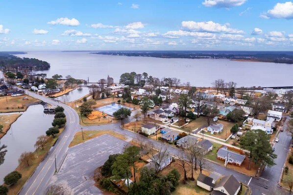 An aerial view of a residential area with houses, a road, and a body of water.