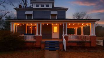 A two-story house with a porch, a front door, and a staircase leading up to the entrance.
