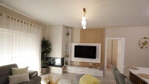 Una sala de estar moderna con sofá, televisor y comedor.