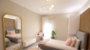 Un dormitorio moderno con un espejo grande, dos camas, un tocador y una mesita.