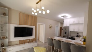 Una cocina moderna con armarios blancos, horno empotrado y refrigerador.