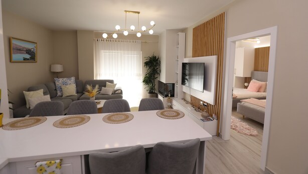 Una sala de estar moderna con comedor, televisor montado en la pared y un dormitorio acogedor.