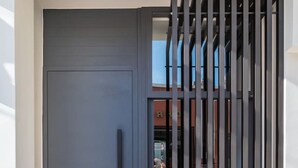 A modern entrance with a dark blue door, a vertical metal gate, and a tiled floor. - Emma's Central Suite (Kos)