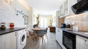 Una cocina moderna con paredes de ladrillo blanco, una zona de comedor con una mesa redonda y sillas, y un horno empotrado.