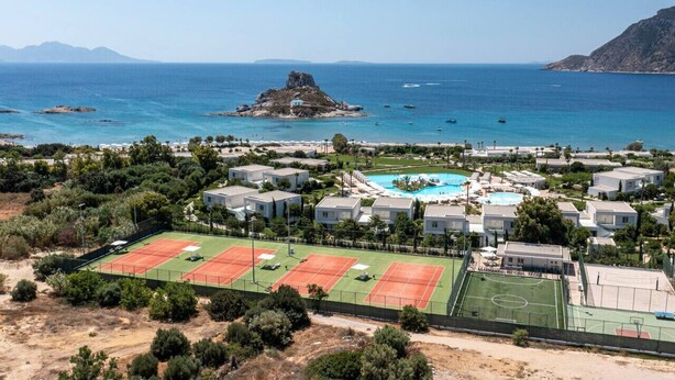 Un complejo turístico frente al mar con varias canchas de tenis, una piscina y villas.