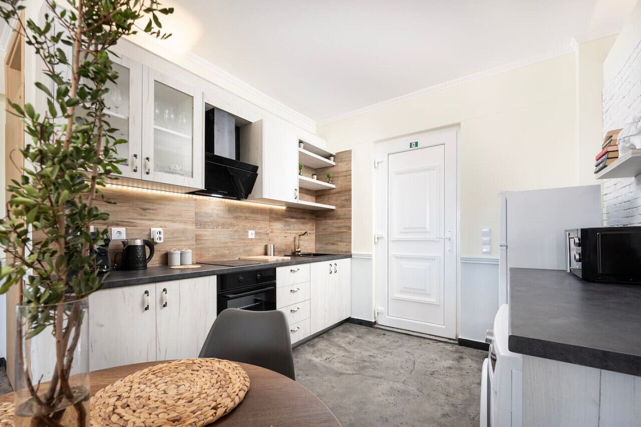 A modern kitchen with white cabinetry, a black stove, and a wooden countertop.