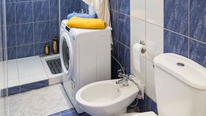 A bathroom with a shower, a toilet, a sink, and a washing machine. - Sunrise Beachfront Getaway (Kardamaina)