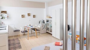 A modern kitchen with white cabinets, a dining table with chairs, a refrigerator, and a microwave. - Sunrise Beachfront Getaway (Kardamaina)