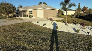 A single-story house with a garage, surrounded by a well-maintained lawn and small shrubs.