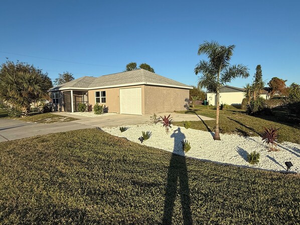 A single-story house with a garage, surrounded by a well-maintained lawn and small shrubs. - Great rental close to all the fun! (Port Charlotte)