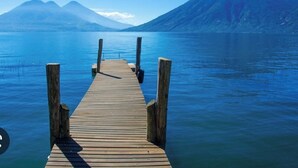 Une jetée en bois s’étendant sur une étendue d’eau calme, avec une montagne en arrière-plan.