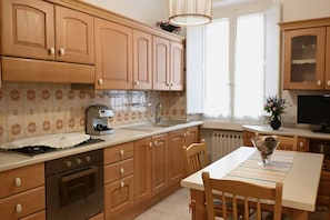 Una cocina con armarios de madera, una estufa, un fregadero y una mesa de comedor con sillas.
