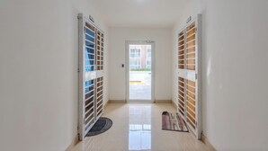 A hallway with a door leading to an outdoor area, a patterned rug, and a metal gate. - Cozy 2 bethoom apartament (Andrés)