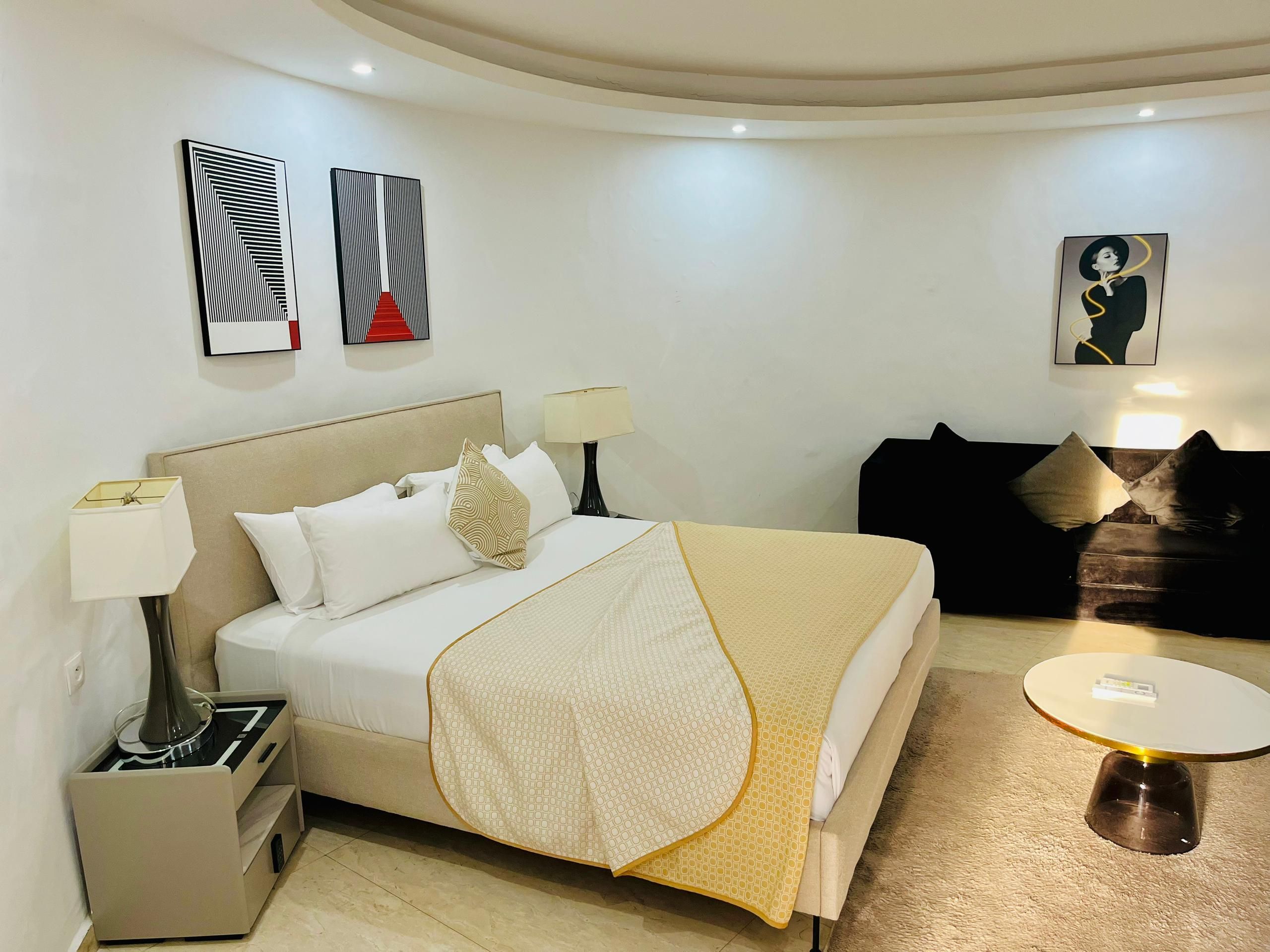 Ein Hotelzimmer mit Bett, Nachttischen, einer Couch und Bildern an den Wänden.