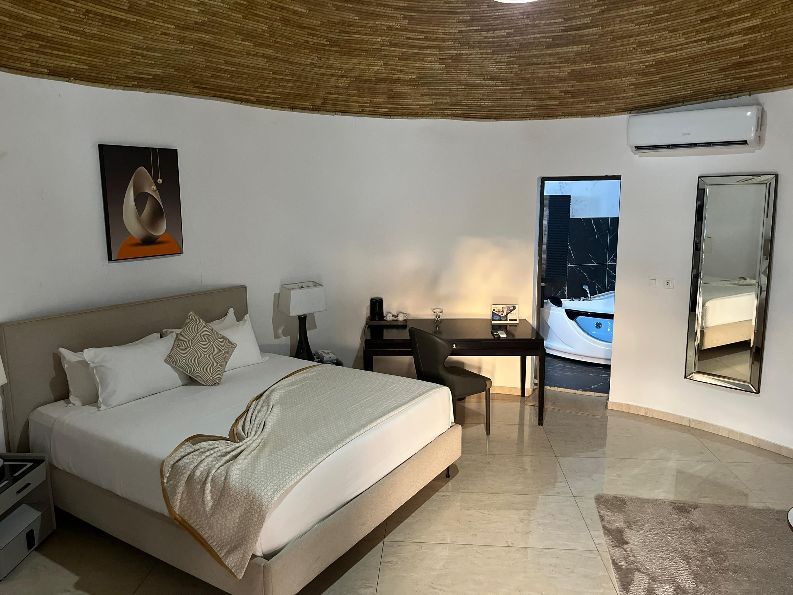 Een hotelkamer met een bed, bureau, stoel en een grote spiegel.