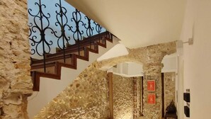 A stone-walled hallway with a wooden staircase and a metal railing. - Casa Rosetta Boutique (Xàtiva)