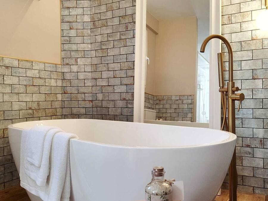 A modern bathroom with a freestanding bathtub, a large mirror, and a pink vanity.