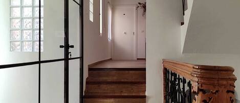 Un hall d’entrée spacieux, doté d’un plancher en bois, d’une porte en verre et d’un escalier avec des rampes en bois.