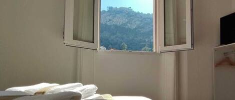 Un dormitorio con una cama, una ventana con cortinas, un televisor y un aire acondicionado instalado en la pared.