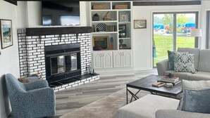 A modern living room with a fireplace, a sofa, a coffee table, and a bookshelf.