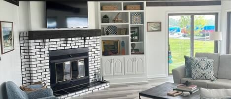 A modern living room with a fireplace, a sofa, a coffee table, and a bookshelf.
