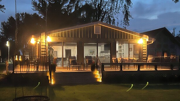 A building with a covered outdoor area, a staircase leading to the entrance, and a lawn in the foreground.
