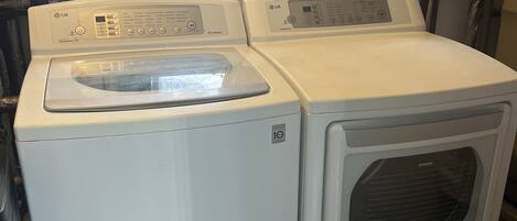 A laundry room with two stacked washing machines, a window, and visible plumbing.