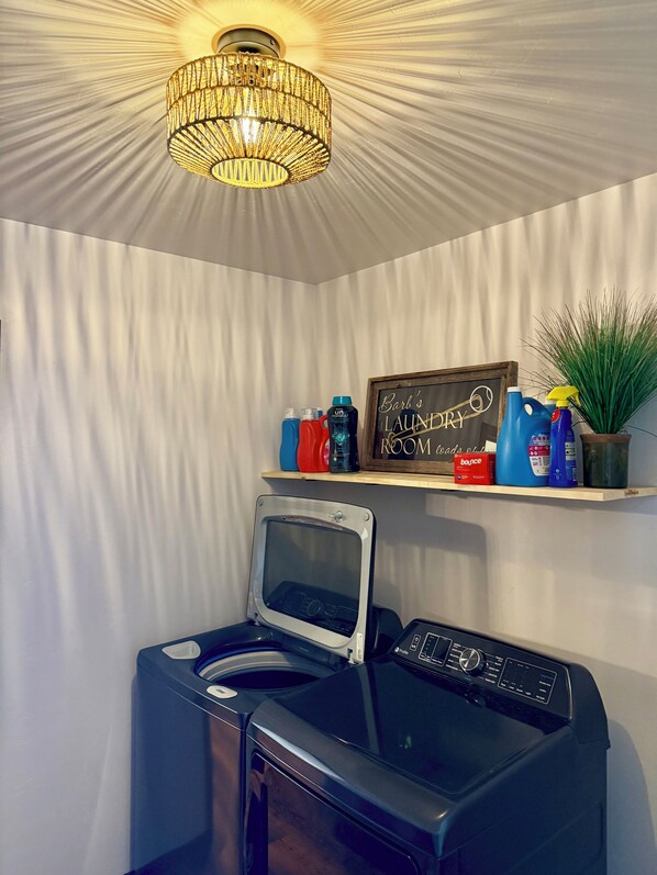 A laundry room with a washing machine, dryer, and a shelf with cleaning supplies.