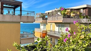 A coastal residential building with balconies, a view of the sea, and a wooden structure on the left. - Tre Ponti Beach Apartment - sea view (Sanremo)