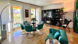 A modern living room with a dining area, a green sofa, a coffee table, and a black cabinet with various items. - Tre Ponti Beach Apartment - sea view (Sanremo)