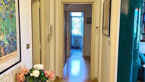 A hallway with a marble floor, framed artwork, a flower arrangement, and a view into a room with a window. - Tre Ponti Beach Apartment - sea view (Sanremo)