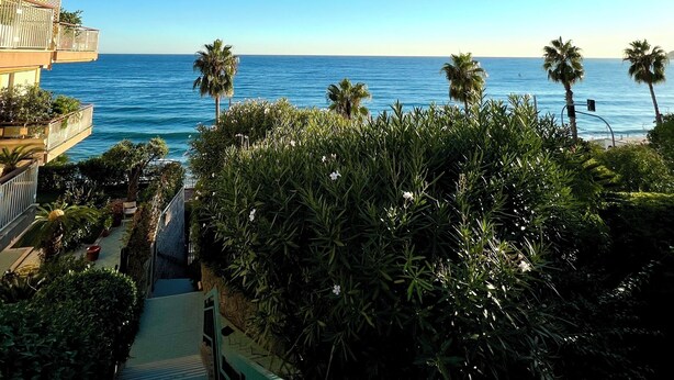 A beachfront hotel with multiple balconies overlooking the sea, a pathway leading to the beach, and lush greenery in the foreground. - Tre Ponti Beach Apartment - sea view (Sanremo)