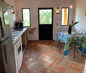 A kitchen with a stove, refrigerator, and dining area with a table and chairs.