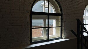 Ein Zimmer mit einem großen Bogenfenster, Backsteinwänden und einer weißen Decke.