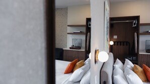 Une chambre d’hôtel avec un lit, des oreillers, un bureau avec un ordinateur et un mur en briques.