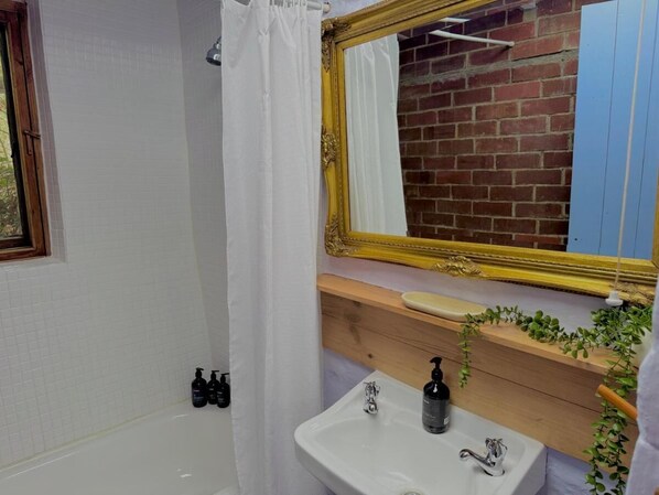 Un bany amb banyera, un lavabo, un mirall i una finestra.