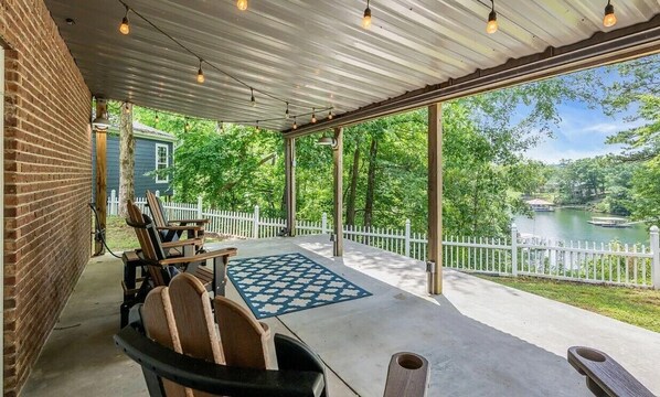A covered patio with outdoor seating, a view of a lake, and a white picket fence. - Waterfront Double Decker Dock - 5 Bed 3 1/2 Bath Smith Lake House in Cullman AL (Cullman)