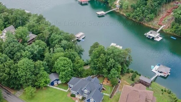 Vista aérea de una zona residencial con casas, un muelle y barcos en un lago.