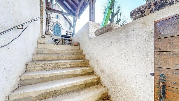 A stone staircase leading to a covered area with a rustic wooden door and a small table with chairs. - 2 bedroom nice home in Volnay (Volnay)