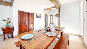 A dining area with a wooden table set for four, a wooden bench, and a potted plant on a small table. - 2 bedroom nice home in Volnay (Volnay)